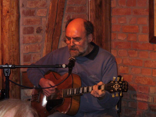 Der Musiker Martin Khn mit seiner Gitarre auf einem Konzert.