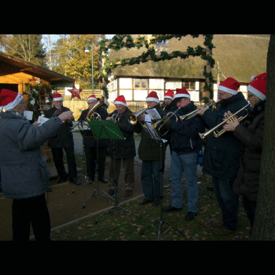 Die Bettmarer Blasmusikgruppe ist hier bei einem Weihnachtskonzert vor einem Haus zu sehen.
