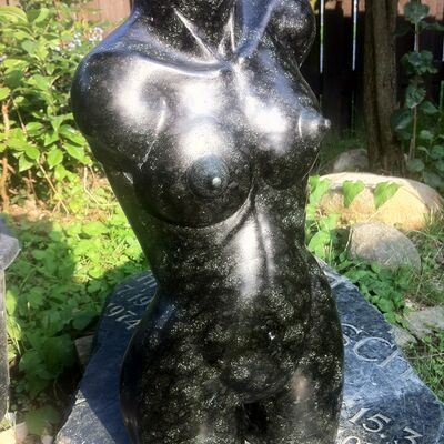 Ein aus schwarzem Stein geschlagener Oberkörper einer Frau.