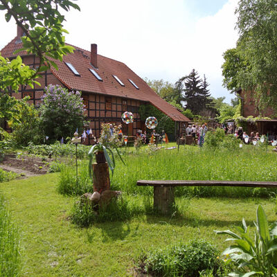 Kunsthof Mehrum, im Garten lässt es sich schön verweilen. Auf dem Bild sind eine charakteristische Bank und Gemüsebeete abgebildet.
