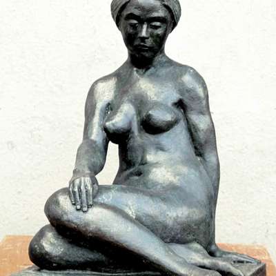 Holger Lassen, der Titel der Skulptur ist nicht bekannt. Eine nackte Frau aus schwarzem Stein sicht mit angewinkelten Beinen auf dem Boden.