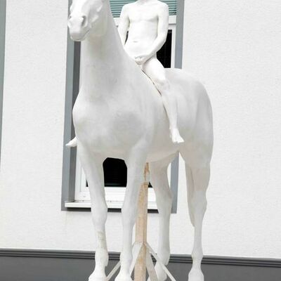 Holger Lassen, der Titel der Skulptur ist: Hengst und Knabe. Eine weiße Knabenskulptur sitzt auf einer weißen Pferdeskulptur.