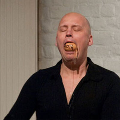 Dr. Helge Meyer, ein Bild auf dem der Performance Künstler Dr. Helge Meyer mit einem Hühner-Ei im Mund zu sehen ist.