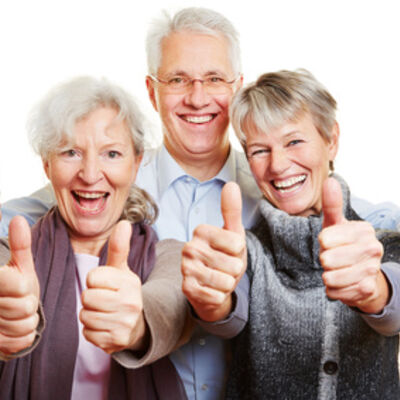 Drei Senioren halten glücklich Daumen hoch