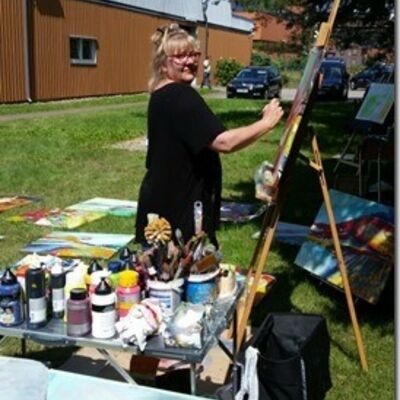 Die Malerin Britta Ahrens vor einer Stafelei mit ihren Malinstrumenten.