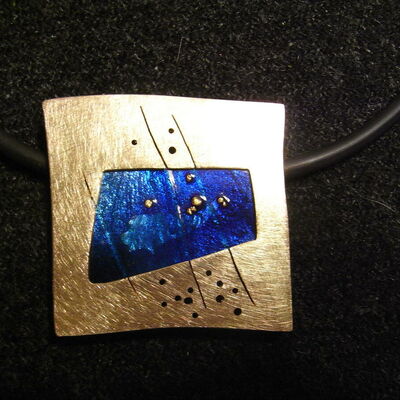Ein Schmuckstück für den Hals, quadratisch und mit gold-blauer Fassung.