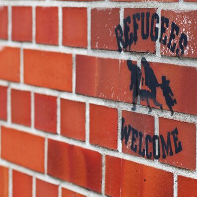 Auf einer Hauswand ist der Spruch "Flüchtlinge willkommen" aufgebracht.