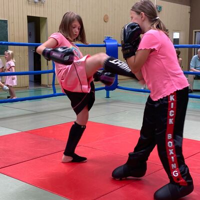 Zwei Mädchen trainieren Kickboxen.