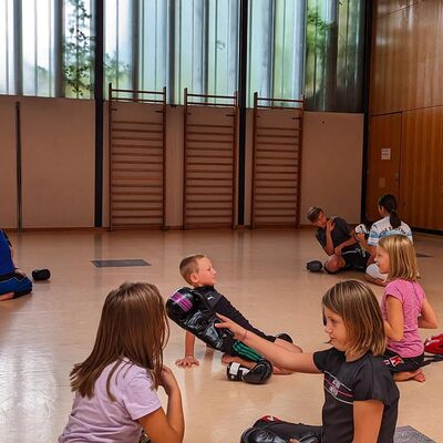 Mehrere Kinder beim Training auf einem Turnhallenboden.